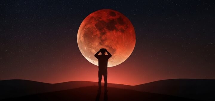 A person using binoculars to observe a total lunar eclipse under a clear night sky, capturing the wonder of the event.